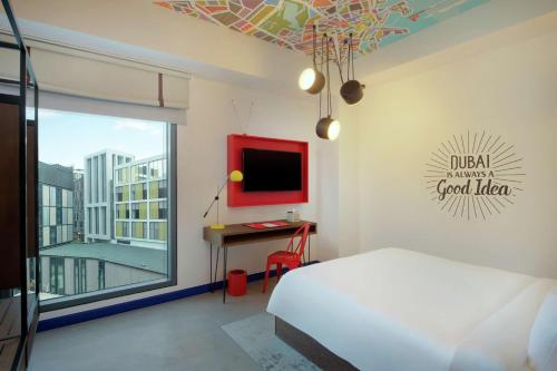 a bedroom with a bed and a desk and a window at Hampton by Hilton Dubai Al Seef in Dubai