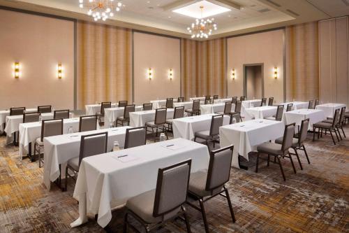 a room with white tables and chairs and chandeliers at Embassy Suites by Hilton South Bend in South Bend