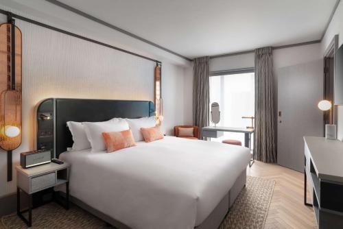 Habitación de hotel con cama blanca grande y escritorio. en Hart Shoreditch Hotel London, Curio Collection by Hilton, en Londres