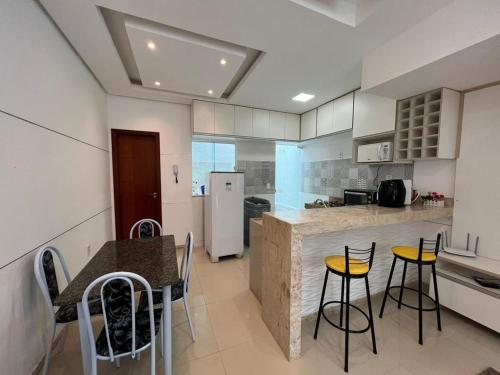 a kitchen with stools and a table and a refrigerator at Villa dos Diamantes - 16 in Porto Seguro