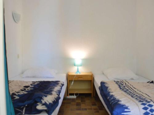 deux lits dans une chambre avec une lampe sur une table dans l'établissement Appartement cosy 2 pièces, clim mobile, près de la plage, 4 couchages, Narbonne Plage - FR-1-229B-84, à Narbonne