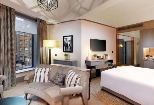 a bedroom with a bed and a couch and a tv at Hart Shoreditch Hotel London, Curio Collection by Hilton in London