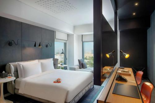 Canopy by Hilton Dubai Al Seef في دبي: غرفه فندقيه بسرير وطاولة واريكه