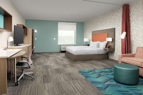 コロンバスにあるHome2 Suites By Hilton Columbus Polarisのベッド、デスク、椅子が備わるホテルルームです。
