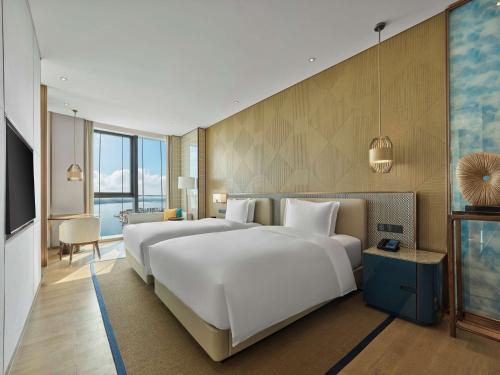 ein Hotelzimmer mit 2 Betten und einem TV in der Unterkunft Hilton Hainan Ocean Flower Island in Danzhou
