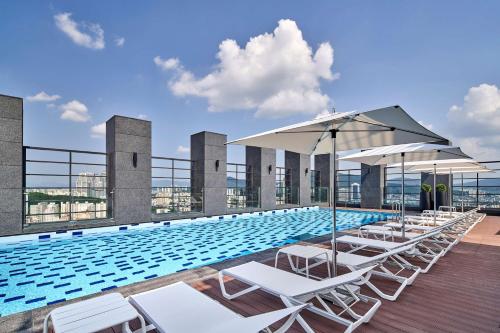 einen Pool mit Stühlen und Sonnenschirmen auf einem Gebäude in der Unterkunft Hilton Garden Inn Seoul Gangnam in Seoul