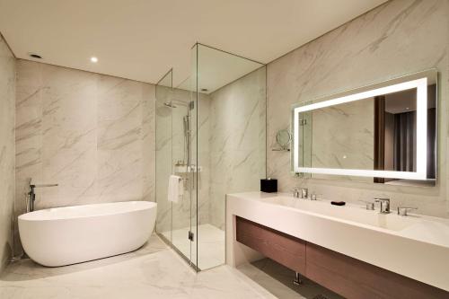 uma casa de banho com uma banheira, um lavatório e um espelho. em Hilton Garden Inn Seoul Gangnam em Seul