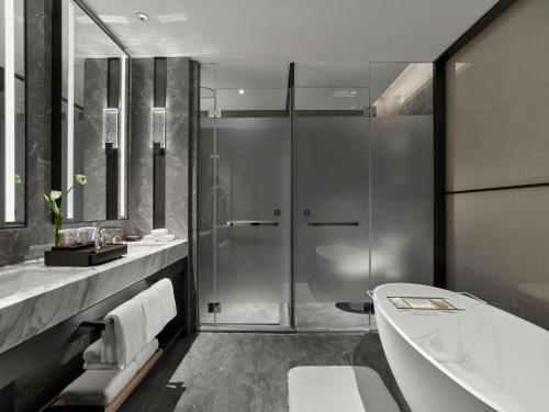 a bathroom with a shower and a tub and a sink at DoubleTree By Hilton Chengdu Riverside in Chengdu