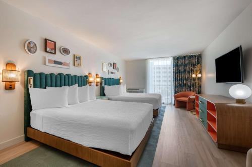 a hotel room with two beds and a flat screen tv at Condado Palm Inn San Juan, Tapestry Collection by Hilton in San Juan