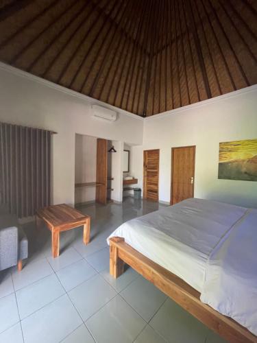 a bedroom with a large bed and a wooden table at El Homestay Bali in Nusa Dua