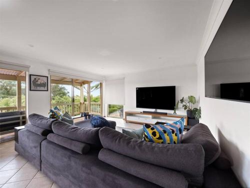 a living room with a large couch and a flat screen tv at Whale Watch Augusta Family Retreat in Augusta