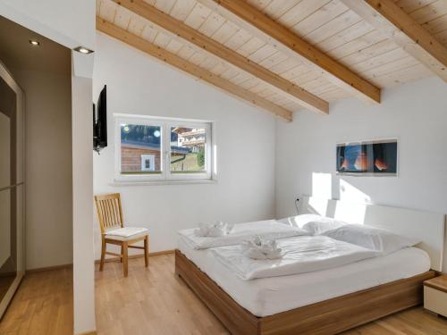 a white bedroom with a bed and a chair at Chalet Pinzgau in Neukirchen am Großvenediger