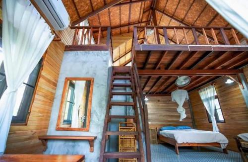 a loft bed in a room with a bed and a ladder at บ้านวารีชีวา WareeCheewa in Ban Muai
