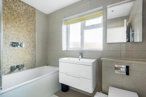 a bathroom with a tub and a sink and a toilet at HARTFORDE HOUSE in Borehamwood