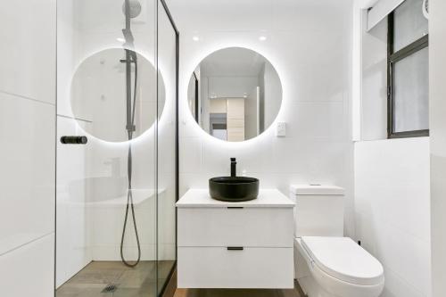 a white bathroom with a toilet and a mirror at The Newstead in Melbourne