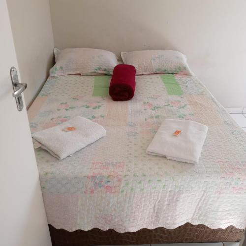 Una cama con dos toallas y un sombrero rojo. en Cantinho do sossego, en Igarapé