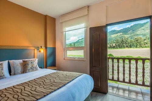 a bedroom with a bed and a large window at Hotel Xue Sabana in Cajicá