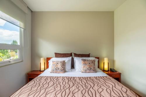 a bedroom with a bed with two lamps and a window at Hotel Xue Sabana in Cajicá