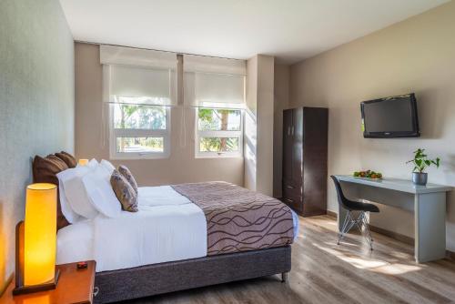 a bedroom with a bed and a desk and a television at Hotel Xue Sabana in Cajicá