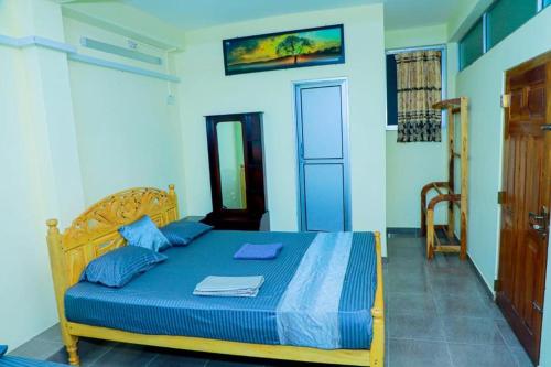 a bedroom with a wooden bed with a blue comforter at UK Inn Guest House in Jaffna