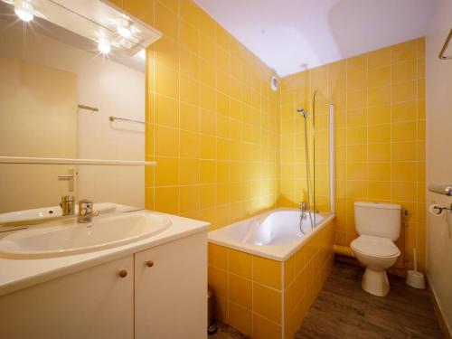 a yellow tiled bathroom with a sink and a toilet at Appartement Peyragudes, 4 pièces, 10 personnes - FR-1-695-18 in Germ