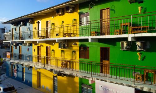 un bâtiment jaune et vert avec une réflexion dans l'eau dans l'établissement Namoasuites, à Maceió
