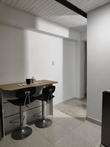 a room with a table and two black chairs at COMODO ESTUDIO VIA A TERMALEs in Santa Rosa de Cabal