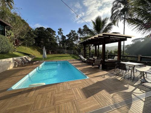 una piscina en una terraza con mesa y sillas en Mega Casa em sítio churrasco piscina em Ipiabas RJ, en Barra do Piraí