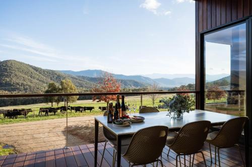 a dining room with a table and chairs on a balcony at Deep Creek Farmstay in Bright