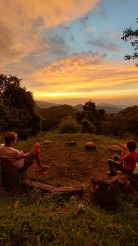 two men sitting on a hill watching the sunset at Finca Hostal Bolivar - Casa Mango in Minca