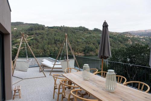 a patio with a wooden table and chairs and an umbrella at Quinta da Ribeirinha - Douro River in Paços de Gaiolo