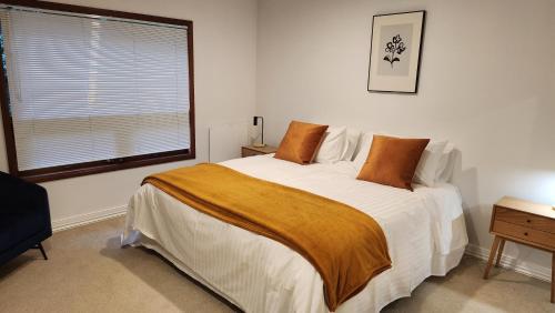 a bedroom with a bed with white sheets and a window at The Black Chalet in Whitianga