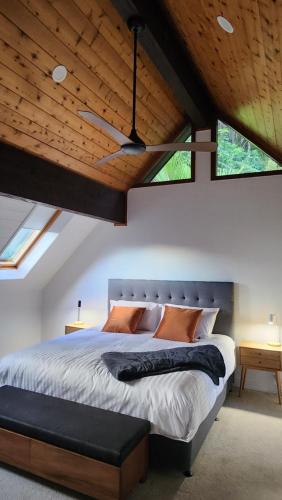 a bedroom with a large bed with wooden ceilings at The Black Chalet in Whitianga