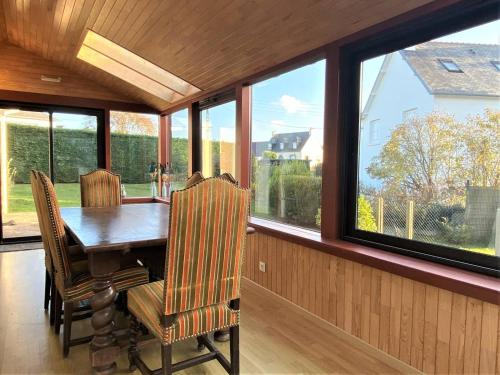 une salle à manger avec une table, des chaises et des fenêtres dans l'établissement Maison avec Jardin, WIFI, proche plage et commerces, calme - Perros-Guirec - FR-1-368-374, à Perros-Guirec