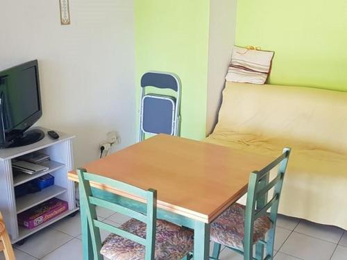 une table à manger avec deux chaises et une télévision dans l'établissement Pavillon à Valras-Plage avec Piscine, à 250m de la Plage, pour 6 Personnes - FR-1-701-58, à Valras-Plage