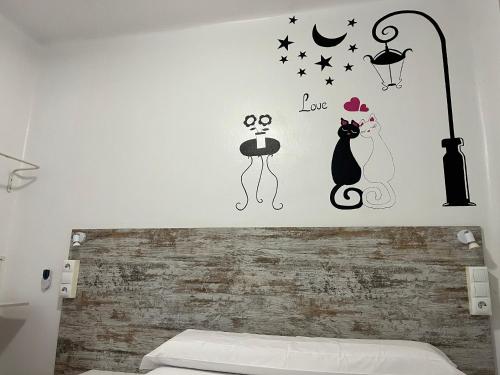 a bedroom with a wall with black cats and a street light at Casa de Huéspedes Almansa in Madrid