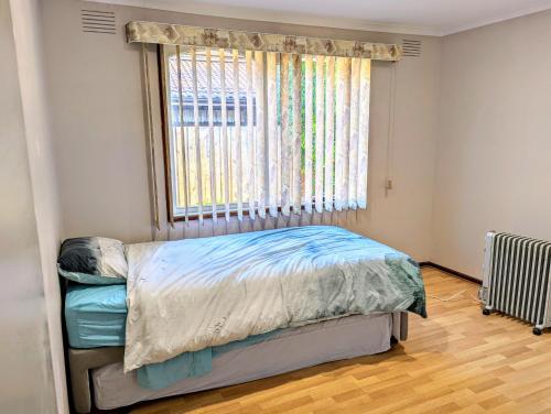 um pequeno quarto com uma cama e uma janela em Corporate Share House em Melbourne