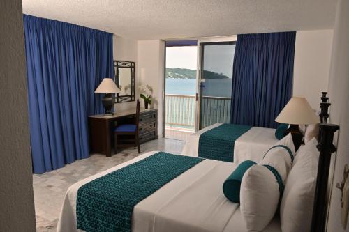 two beds in a hotel room with a view of the ocean at Ritz Acapulco All Inclusive in Acapulco