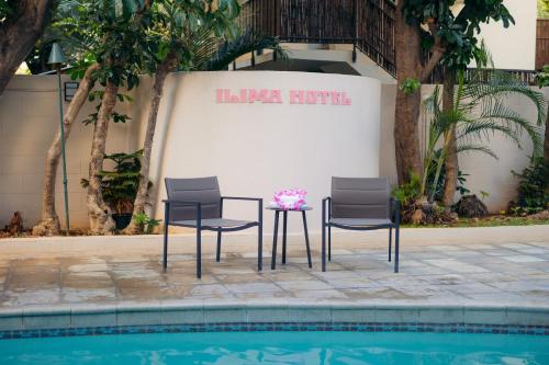 2 Stühle und ein Tisch neben einem Pool in der Unterkunft Ilima Hotel in Honolulu