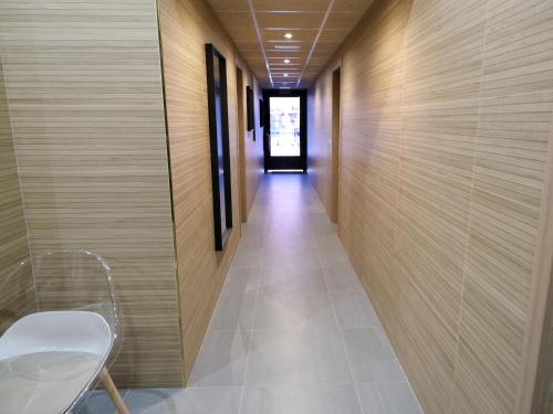 un pasillo con paredes de madera y una silla blanca en Alianza Suites en Madrid