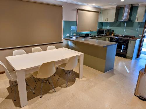 kuchnia z białym stołem i krzesłami w obiekcie Corporate Share House w Melbourne