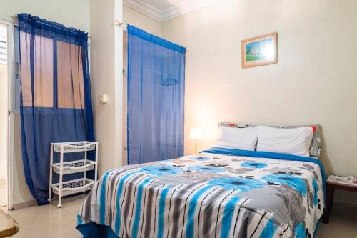 a bedroom with a bed and a window with blue curtains at Habitación cerca al Mar, Obelisco Hembra y Zona Colonial in Santo Domingo