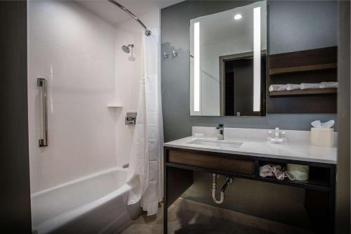 a bathroom with a sink and a tub and a mirror at Hilton Garden Inn West Palm Beach I95 Outlets in West Palm Beach