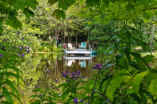 a dock in the middle of a lake with a chair on it at 13-Acre Private Estate, Private Lake, Private Golf Range, Private Forest & Hiking Trails in Ross Corner