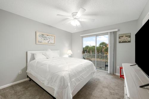 a white bedroom with a bed and a window at Barefoot Bungalow in Panama City Beach