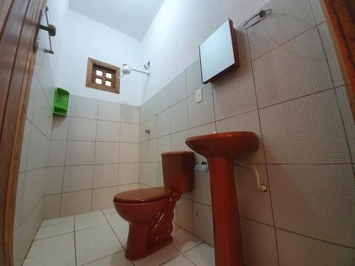 ein Bad mit WC und ein TV an der Wand in der Unterkunft Sunrise Inn - Pousada Nascer do Sol in Ituberá
