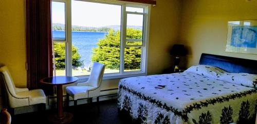 a bedroom with a bed and a view of the water at St Ann's Motel & Cottage in Baddeck