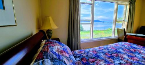 a bedroom with a bed and a large window at St Ann's Motel & Cottage in Baddeck