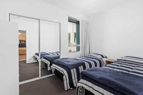 a bedroom with two beds and a mirror at Beachside on Brakes in Gold Coast