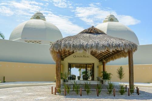 Blick auf ein Gebäude mit einem Strohschirm in der Unterkunft Quinta Real Huatulco in Santa Cruz Huatulco
